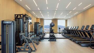 A gym with cardio equipment, weight machines, and a view of the city.