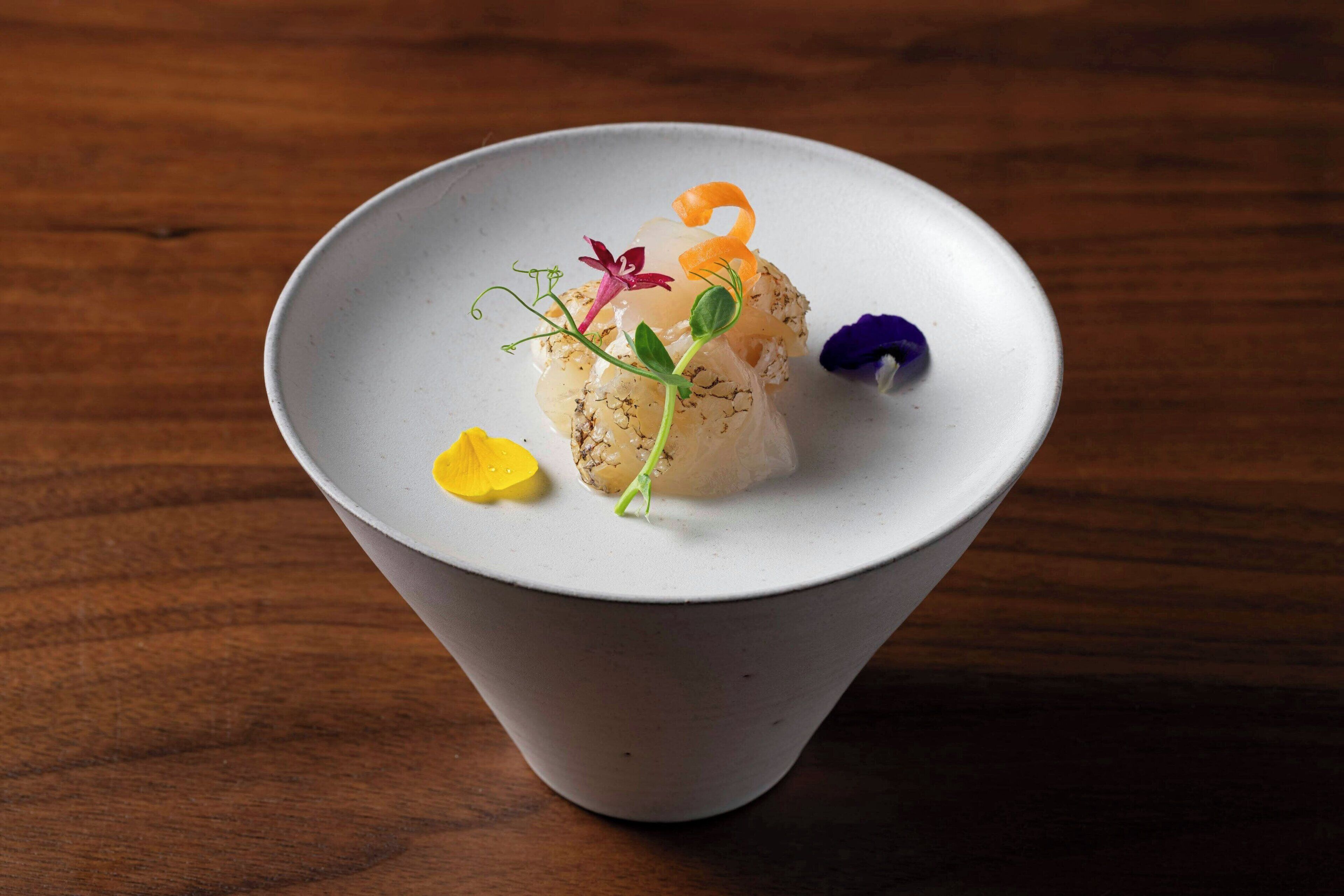 Un tazón de cerámica blanca con un plato de comida sobre una mesa de madera.
