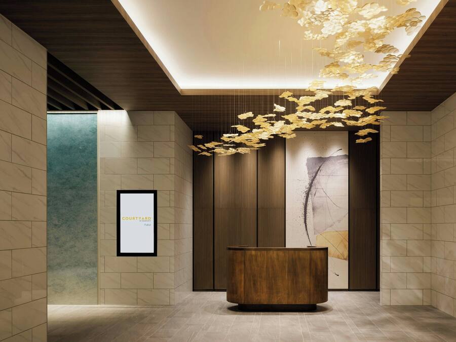 Un vestíbulo moderno con un mostrador de recepción de madera, una obra de arte enmarcada en la pared y una lámpara de techo original.