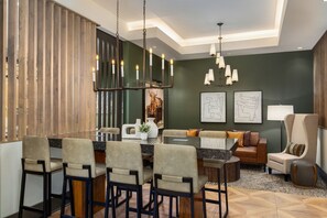 Un comedor moderno con una isla central, taburetes de bar y una araña.