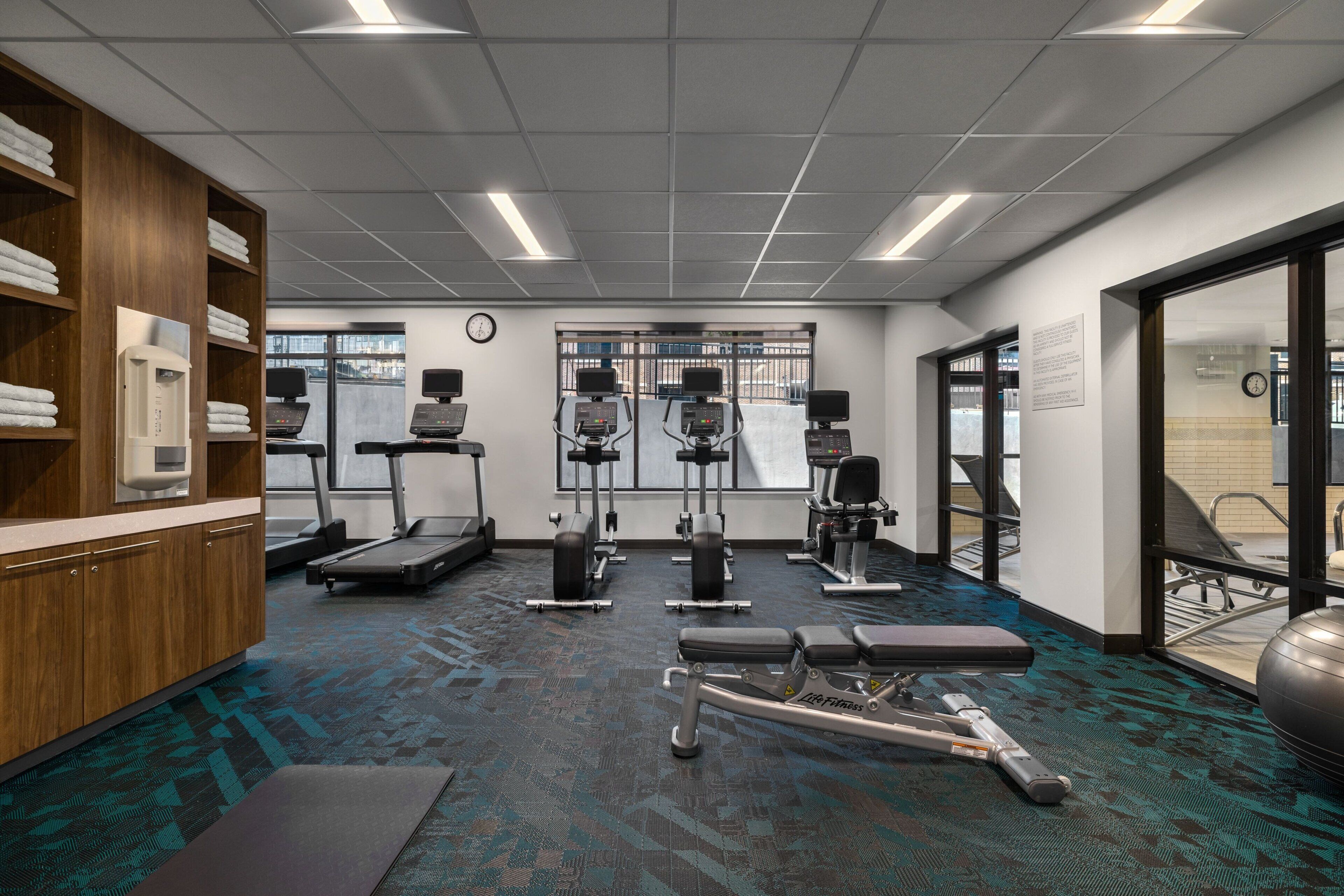 Un gimnasio con cintas de correr, máquinas de pesas y una banca.