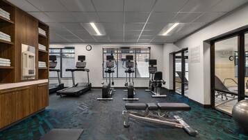 Un gimnasio con cintas de correr, máquinas de pesas y una banca.