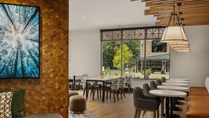 A modern dining area with hexagonal patterned walls, a large window offering a view of the outdoors, and a variety of seating options including tables and chairs. - Towneplace Suites By Marriott Memphis Germantown (Germantown)