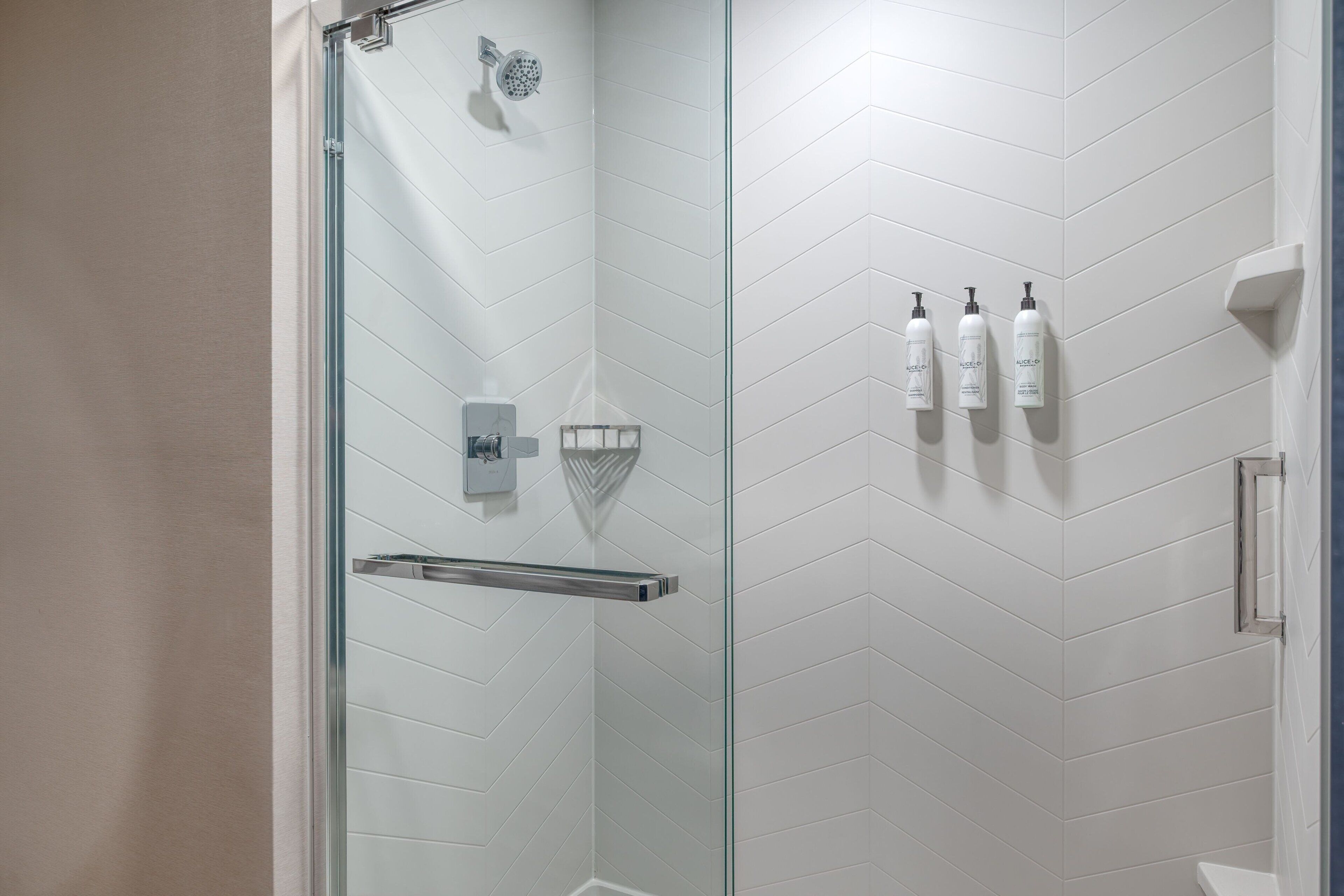 Een moderne badkamer met een douchecabine van glas, witte betegelde wanden en een glazen deur.