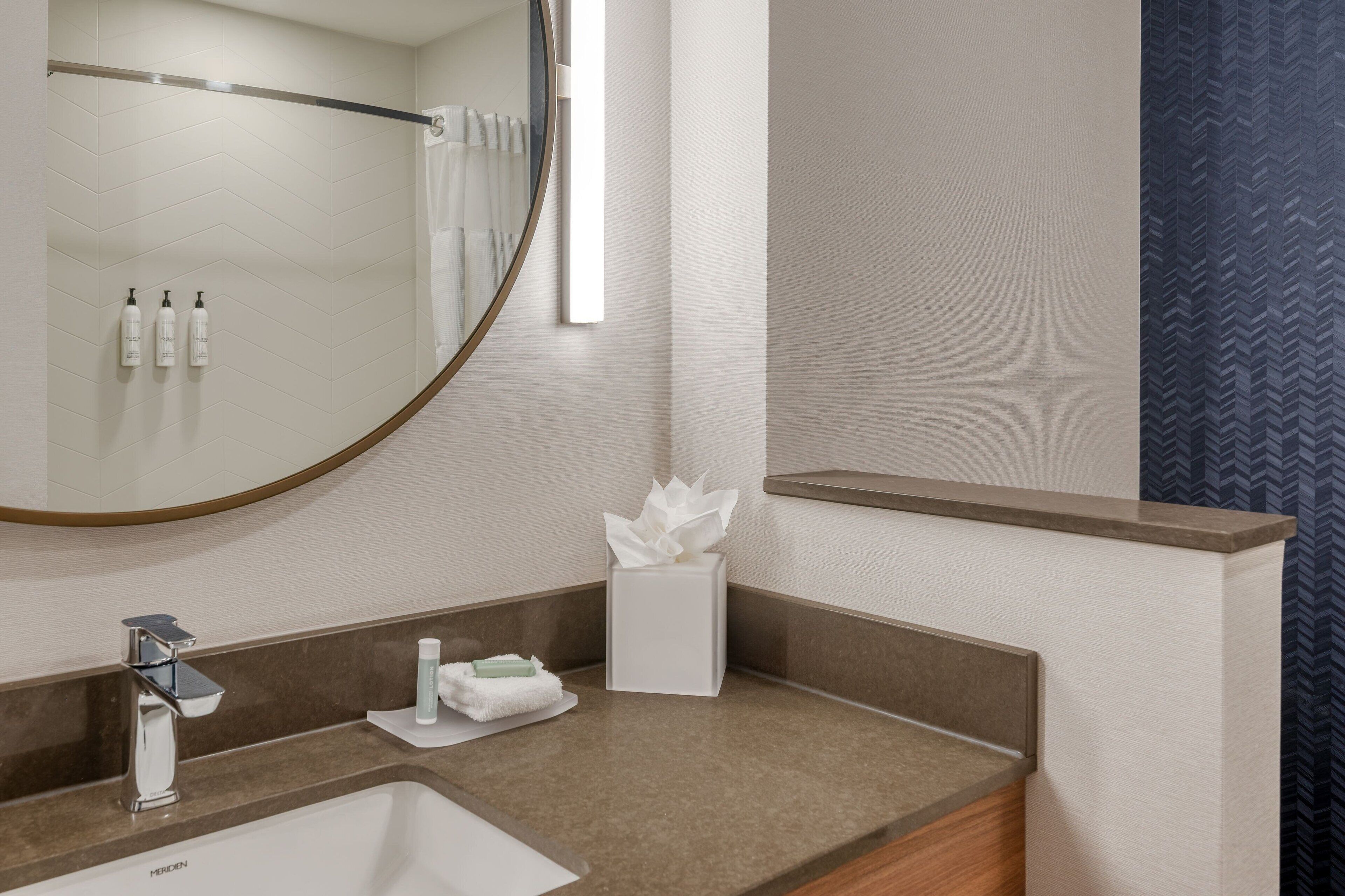 A bathroom with a sink, mirror, towel rack, and toiletries.
