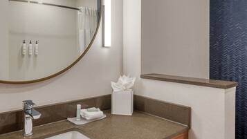 A bathroom with a sink, mirror, towel rack, and toiletries.
