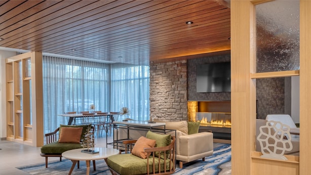 Una sala de estar moderna con chimenea de piedra, techo de madera y comedor con mesa y sillas de vidrio.