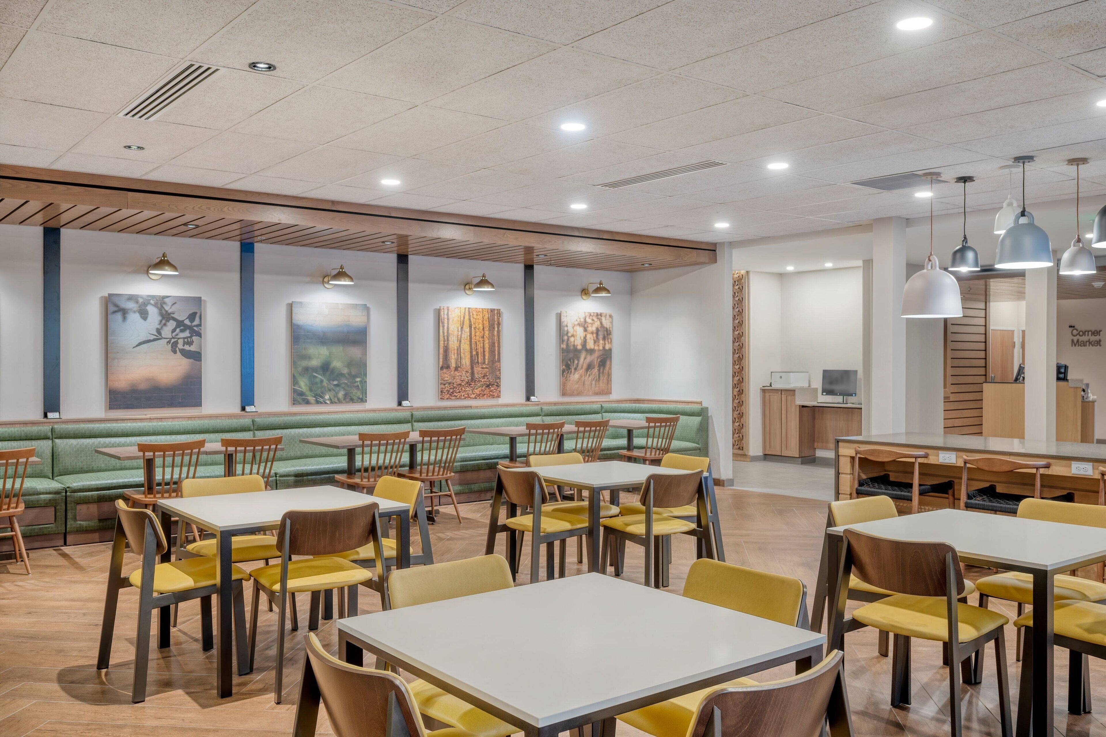 Un restaurante moderno con asientos verdes, sillas amarillas y mesas blancas.