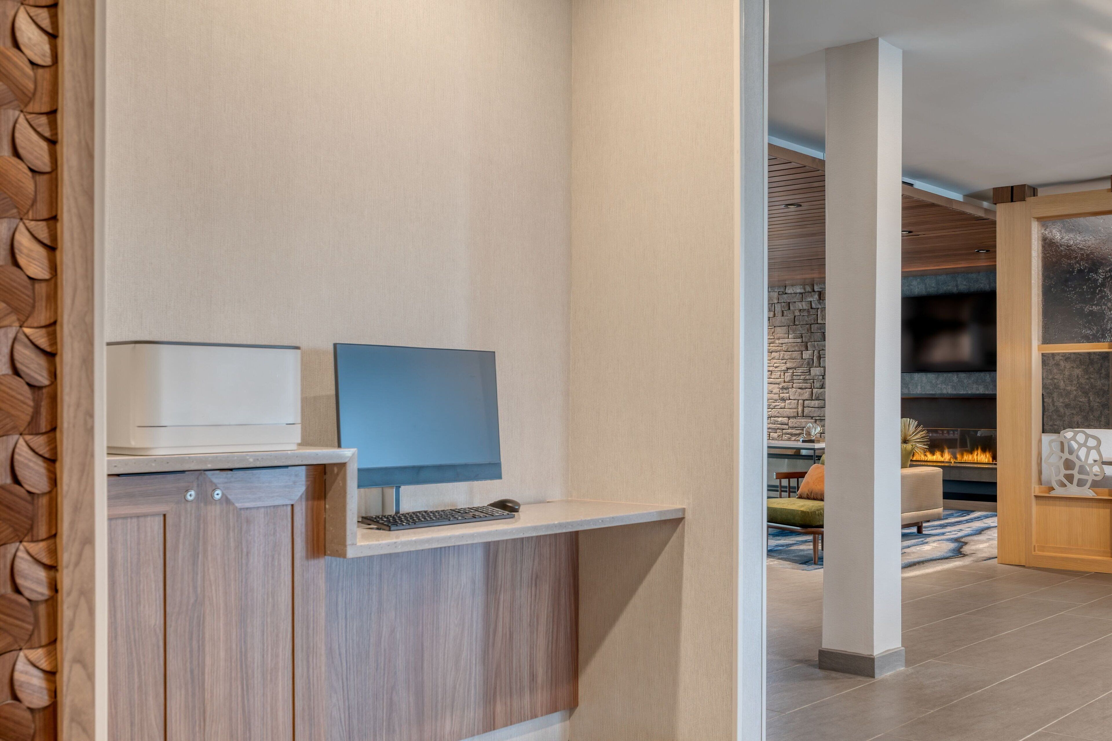 Una moderna reception con un computer, un armadietto in legno e una parete in pietra sullo sfondo.