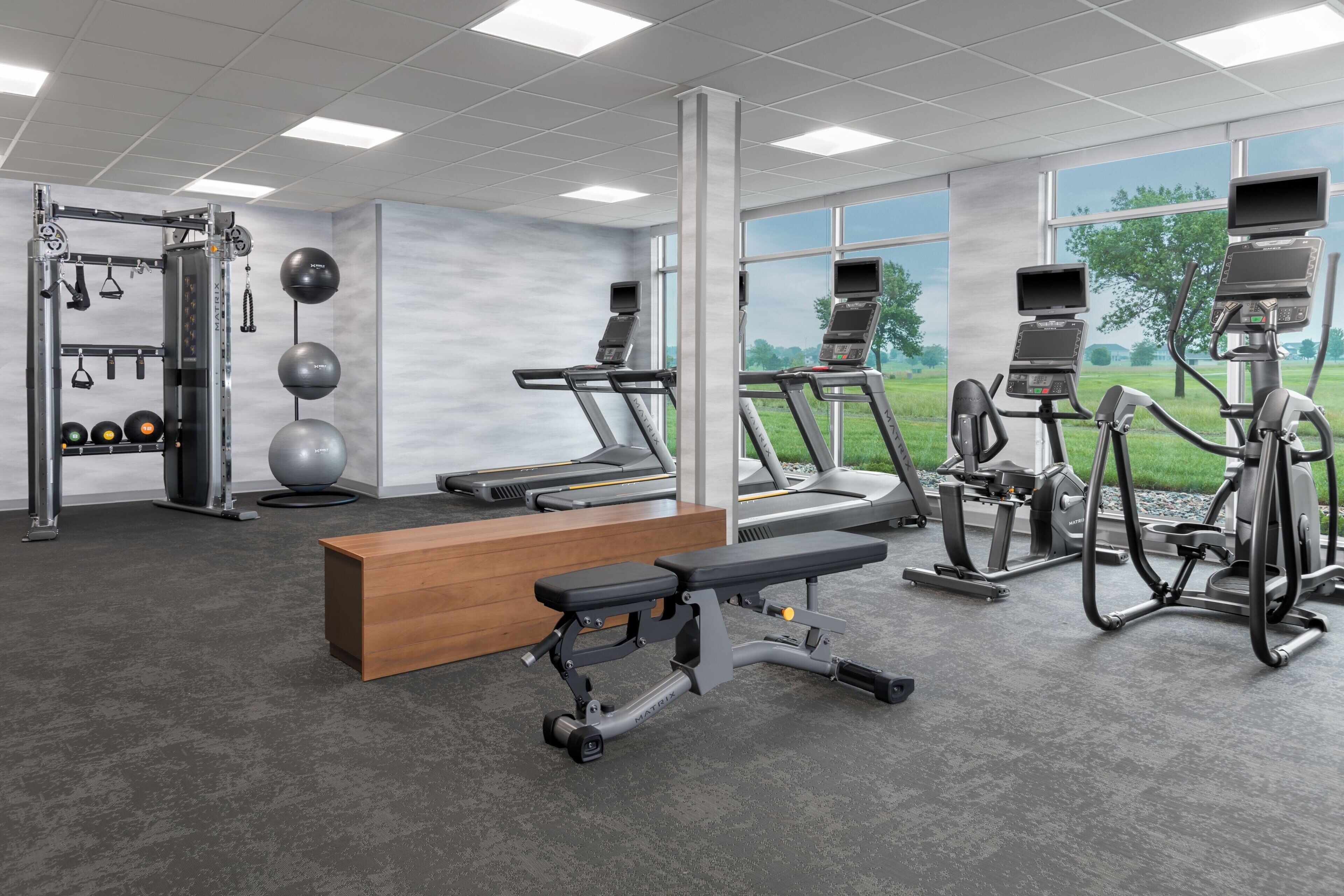 Una palestra con tapis roulant, ellittiche, una panca e attrezzature per sollevamento pesi.