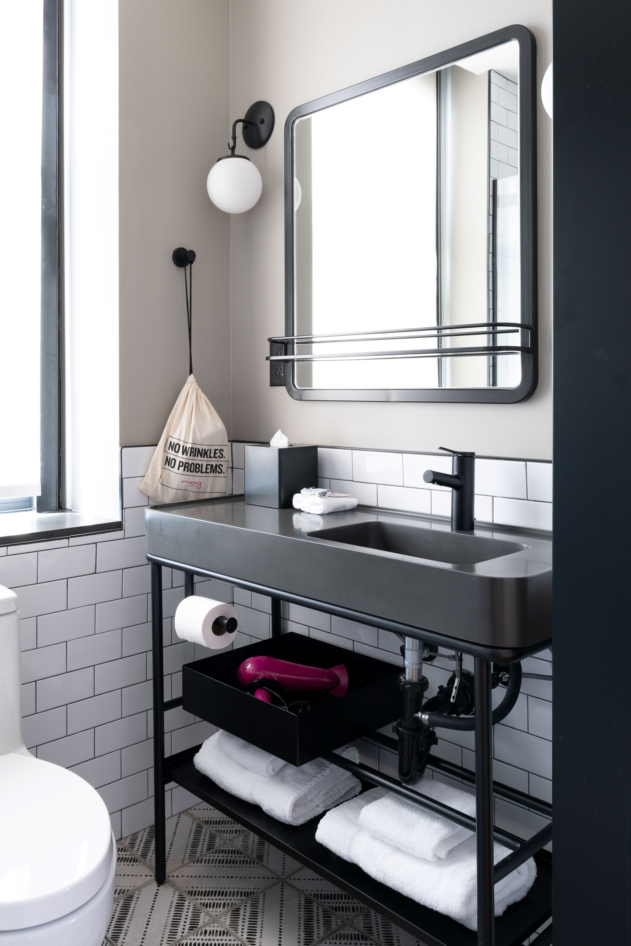 A modern bathroom with a black sink, a mirror, a towel rack, and a toilet.
