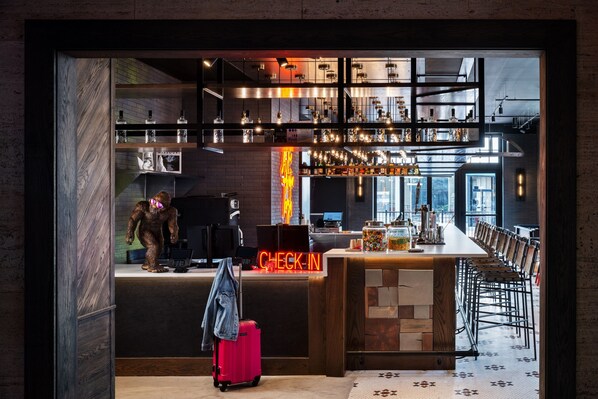 Uma área de bar moderna com balcão de check-in, assentos e cozinha visível ao fundo.
