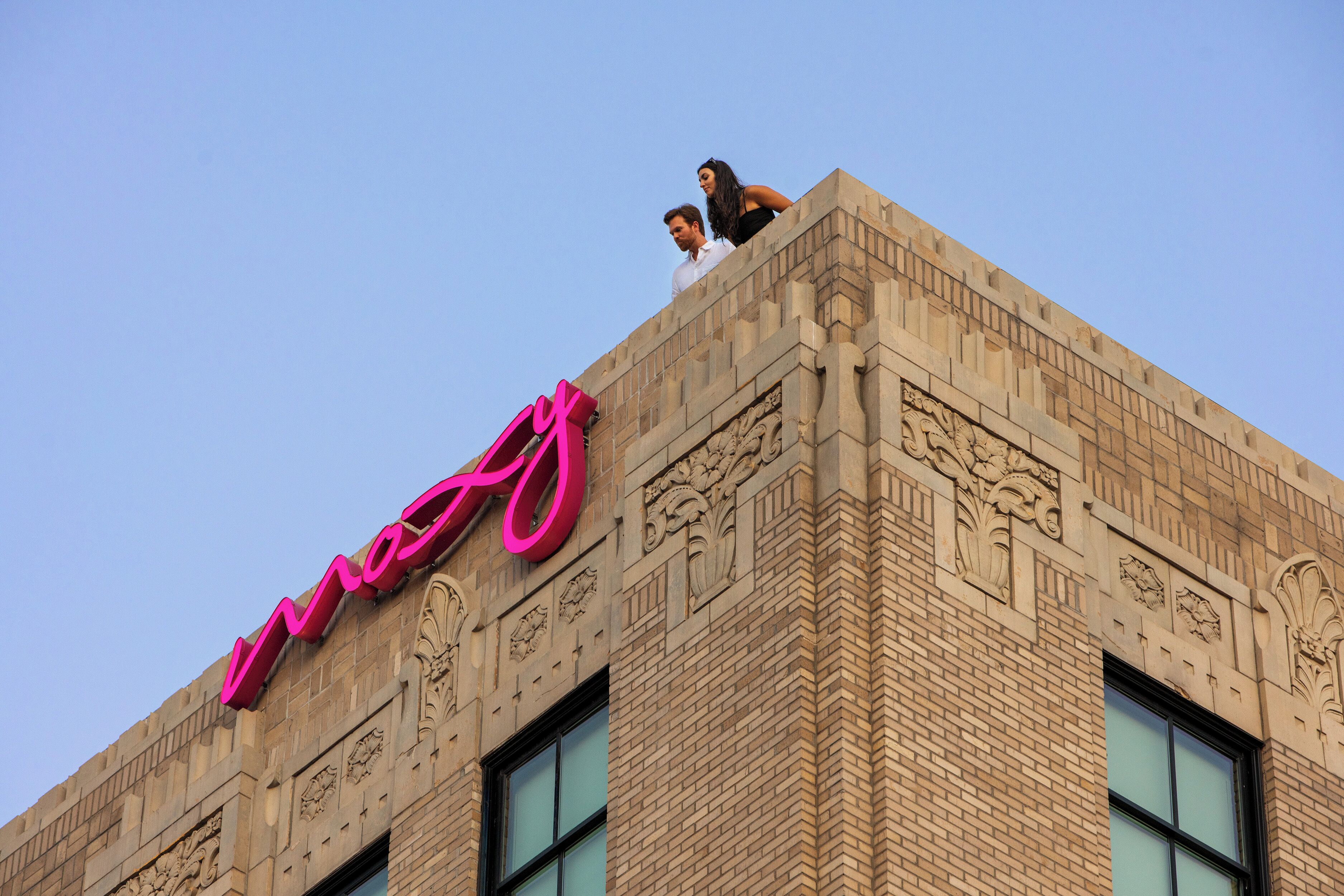 Un edificio con un llamativo letrero rosa y detalles arquitectónicos elaborados.