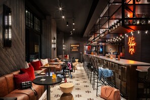 Um espaço de bar moderno com assentos de couro, mesas de madeira e um letreiro de neon.