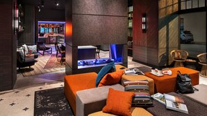 Un hall d'entrée moderne avec une cheminée, un coin salon et un bar en arrière-plan.