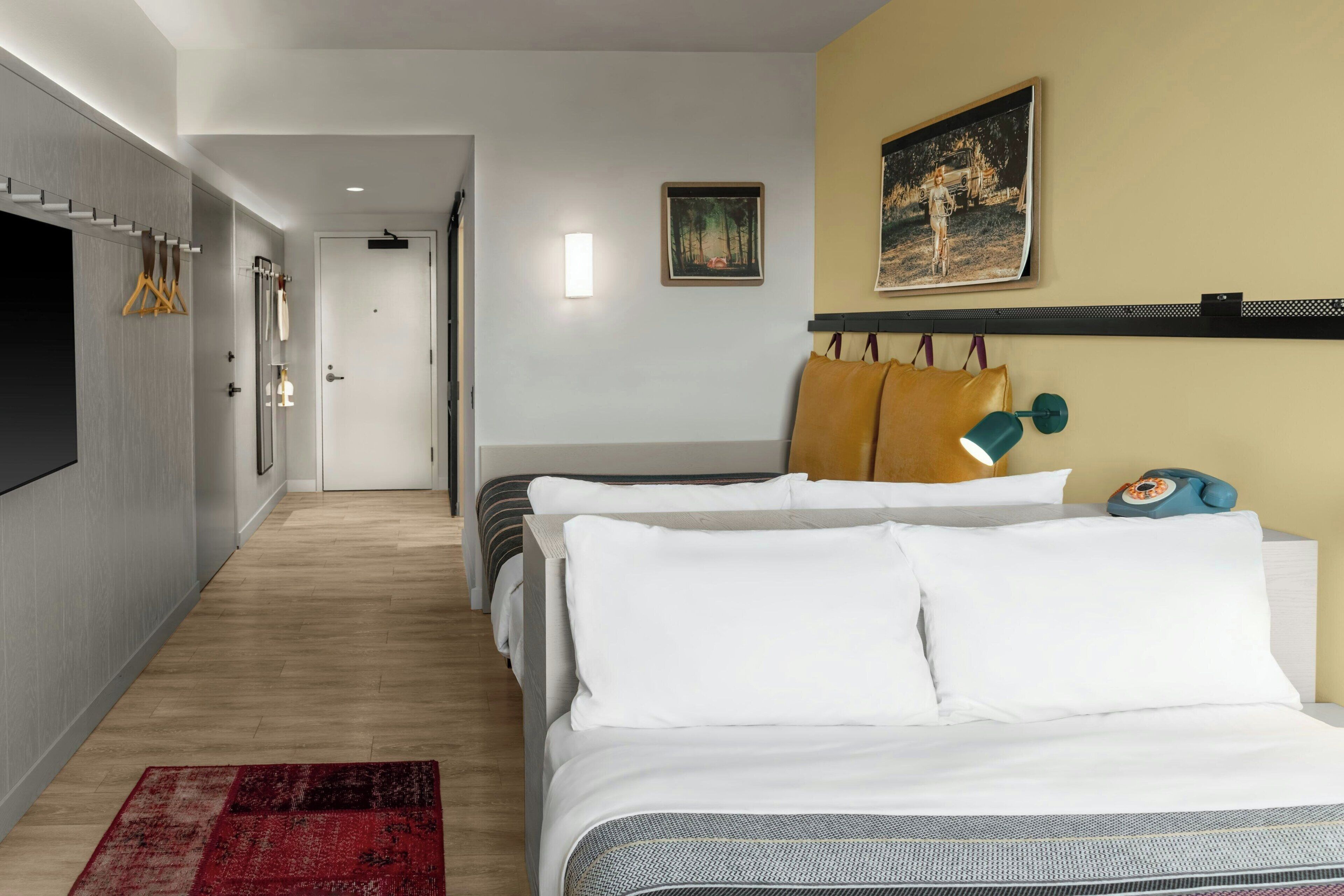 Habitación de hotel con una cama, un escritorio, una silla, una lámpara de escritorio, un teléfono y un cuadro en la pared.