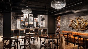 Un espace bar avec des tables et des chaises en bois, un comptoir et un présentoir à bouteilles.