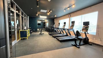 Un gimnasio con cintas de correr, pesas y un muro de espejos.