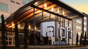 A hotel with a modern architectural design, featuring a prominent 'aloft' sign and a covered entrance area. - Aloft by Marriott McAllen (McAllen)