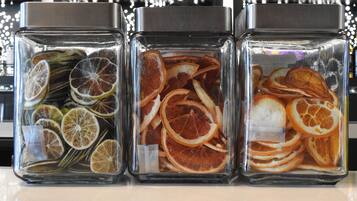 Three glass jars filled with dried citrus slices, likely used for making beverages, placed on a counter with a bar in the background.