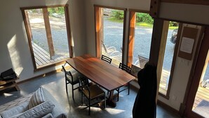 Un comedor con una mesa y sillas de madera, ventanas amplias y vistas al exterior.