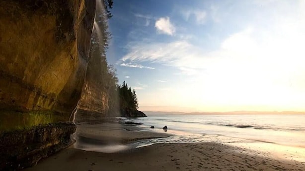 Una playa con un risco y vista al océano.