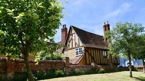 Une maison traditionnelle de style Tudor, avec un mur en briques, un toit de chaume et des cheminées.