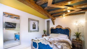Une chambre avec un grand lit, un miroir, un tableau encadré et un plafond en bois.