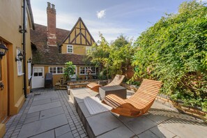 A courtyard with a wooden bench, a stone table, and a small garden area. - Executive Suite With Private Hot Tub Skytv (Saffron Walden)