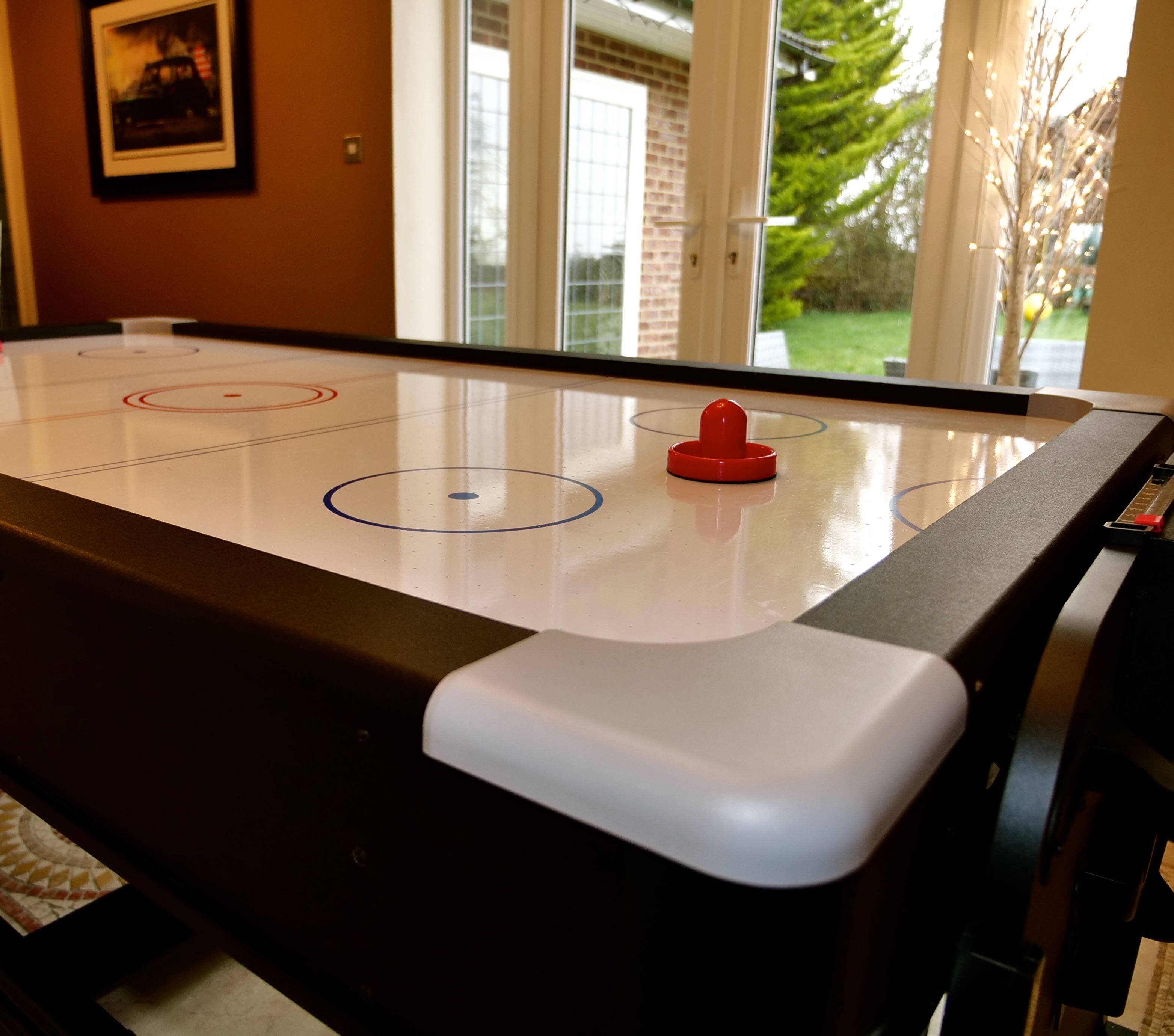 Un jeu de hockey sur table avec un palet rouge et une table blanche.