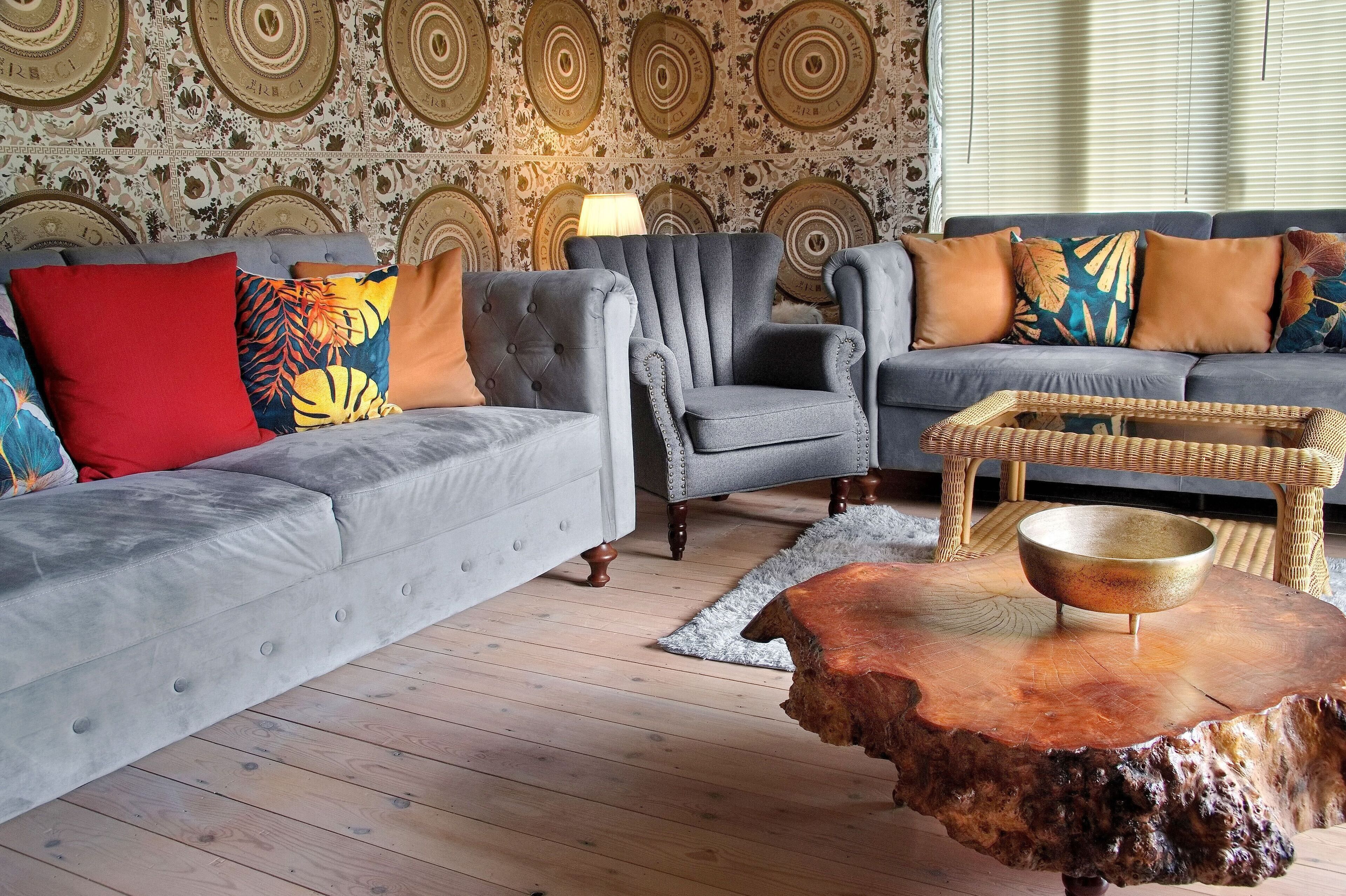 A living room with a grey sofa, a grey armchair, and a wooden coffee table with a bowl.
