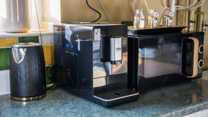 Een keuken met een koffieapparaat, waterkoker en een magnetron.