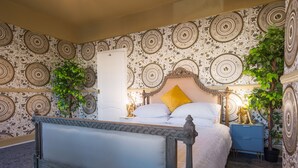 Een slaapkamer met een groot bed, een nachtkastje en twee potplanten.