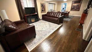 A living room with a fireplace, leather sofas, a TV, and a dining area.