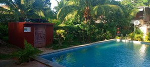 Relax by the serene pool surrounded by lush greenery and palm trees.
