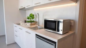 Cozinha moderna com armários brancos, micro-ondas embutido e lava-louças.