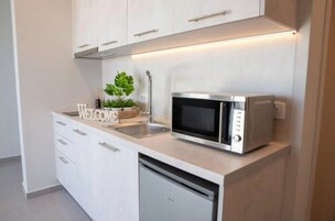 Una cocina moderna con armarios blancos, microondas integrado y lavavajillas.