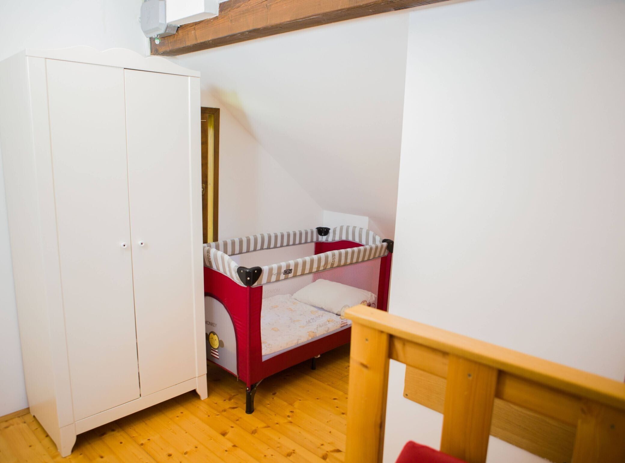 Une petite pièce avec un lit superposé, une armoire blanche et une chaise en bois.