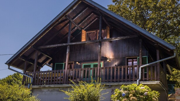 Ein Holzhaus mit Balkon, einer Treppe und einem Garten mit Hortensien.