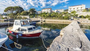Un port de plaisance avec des bateaux amarrés, une jetée en pierre et des immeubles d’habitation en arrière-plan.