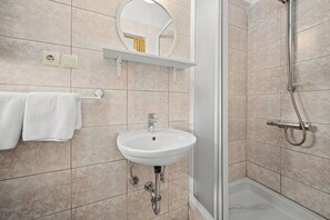 Bathroom features a pedestal sink, mirror, and shower area with a showerhead and control panel.