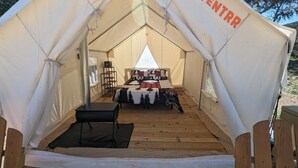 A tent with a bed, a table, and a chair inside. - Glamping Tents 1, 2, 3 (Vanderpool)