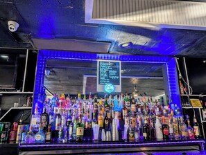 A bar area with a variety of liquor bottles and a chalkboard menu listing beer options. - Fairmount Inn & Suites -Stroudsburg (Delaware Water Gap)