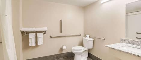Un baño con inodoro, barras de apoyo, toallero y cortina de ducha.
