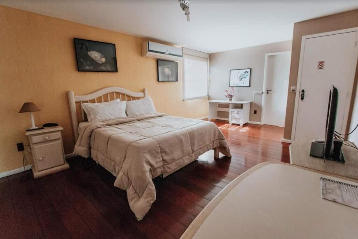 Un dormitorio con cama, mesita de noche y un escritorio pequeño con silla.