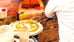 Forno de pizza de tijolos com uma pizza sendo preparada dentro.