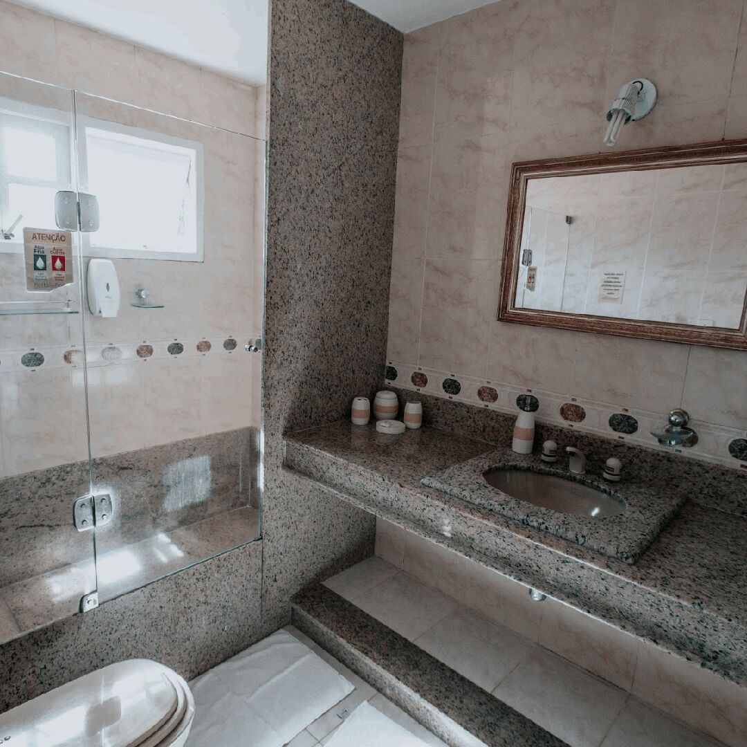 Un baño con encimera de granito, lavamanos, espejo y cabina de ducha de vidrio.