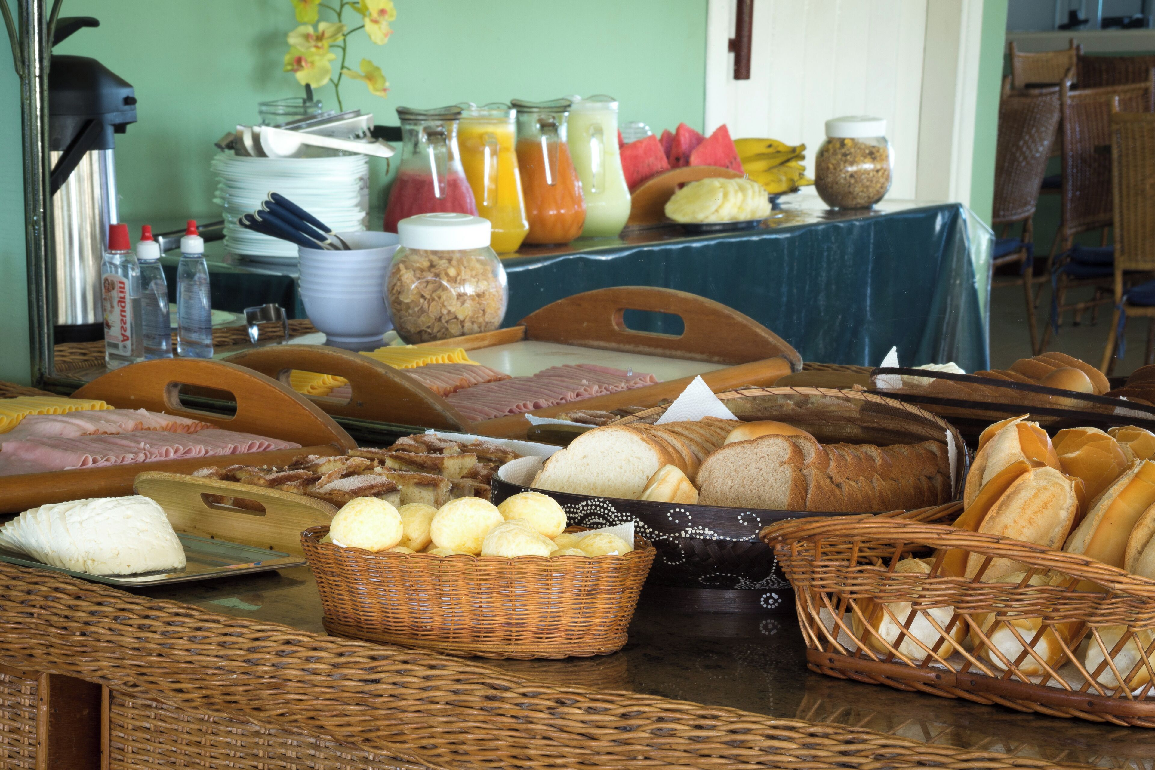 A breakfast buffet with various breads, pastries, and beverages.