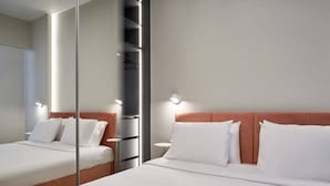 A hotel room with two beds, a mirror, and a wardrobe. - Little Gem: Modern Urban Retreat (Athina)