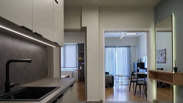 A modern kitchen with a built-in sink and a dining area with a table and chairs. - Little Gem: Modern Urban Retreat (Athina)